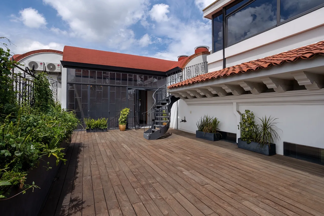 Terraza de madera con teja de barro, jardineras y escalera de caracol