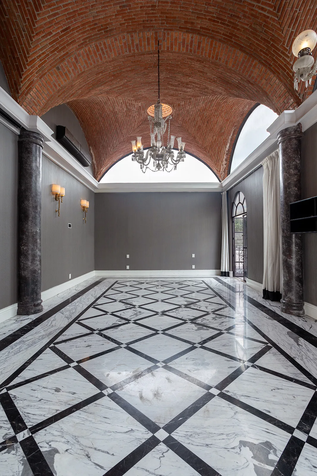 Salón de bóveda visto a lo largo, con candil de cristal y piso de mármol en trazo geométrico