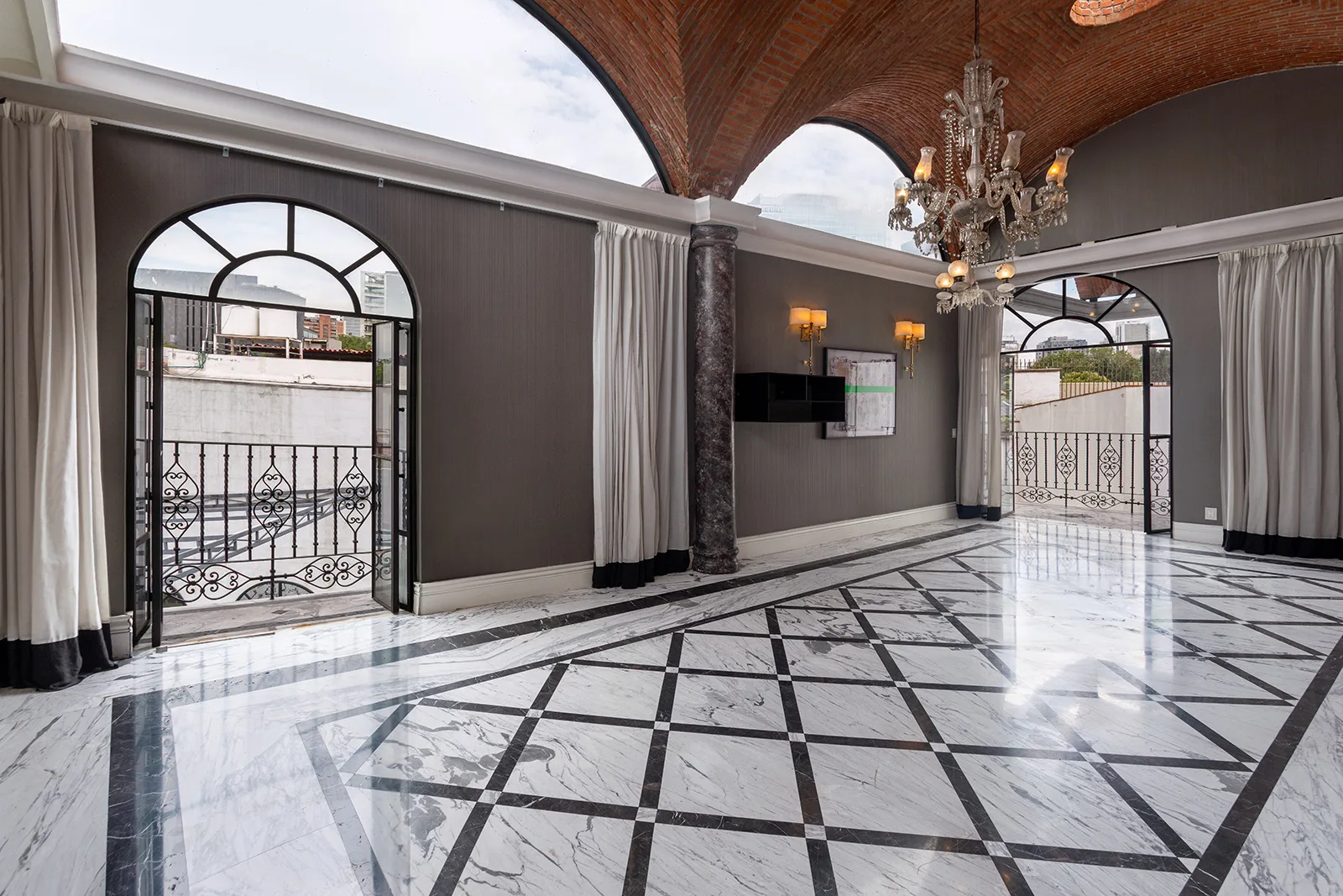 Salón principal con bóveda de ladrillo, columnas de mármol y ventanales arqueados de herrería